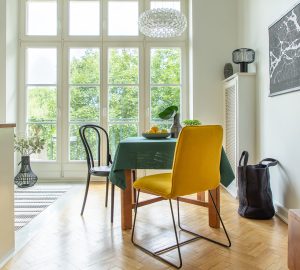 Large kitchen diner with wooden table with green table cloth and bowl of lemons. Large french doors and wooden flooring