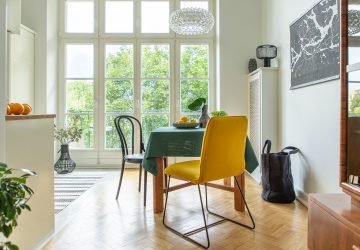 Large kitchen diner with wooden table with green table cloth and bowl of lemons. Large french doors and wooden flooring