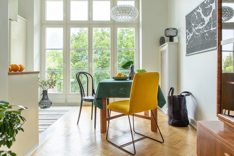 Large kitchen diner with wooden table with green table cloth and bowl of lemons. Large french doors and wooden flooring