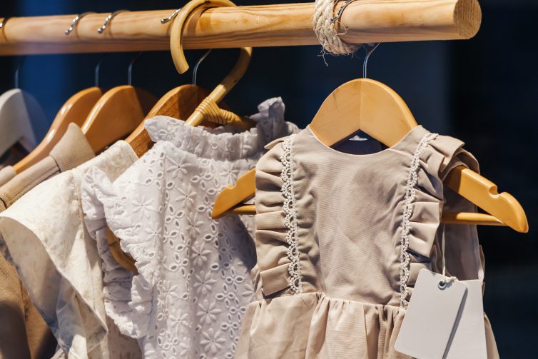 Childrens dresses hanging on homemade curtain pole made of wood pole and rope