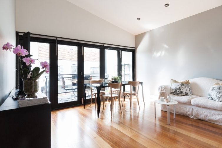 Large living room with wooden flooring. Bifolding doors onto balcony with table and chairs