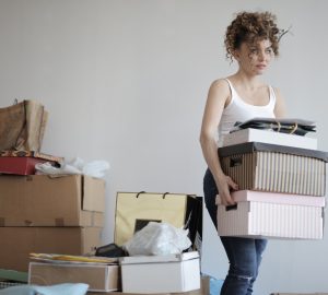 Women carying storage boxes in cluttered room