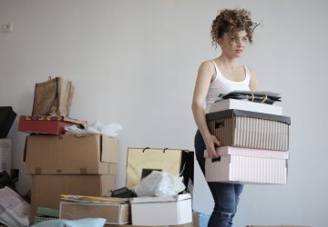 Women carying storage boxes in cluttered room