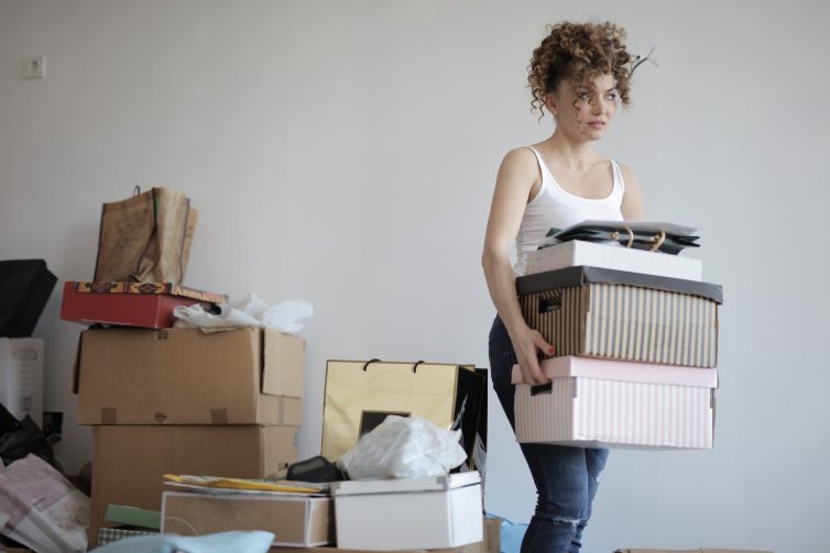 Women carying storage boxes in cluttered room