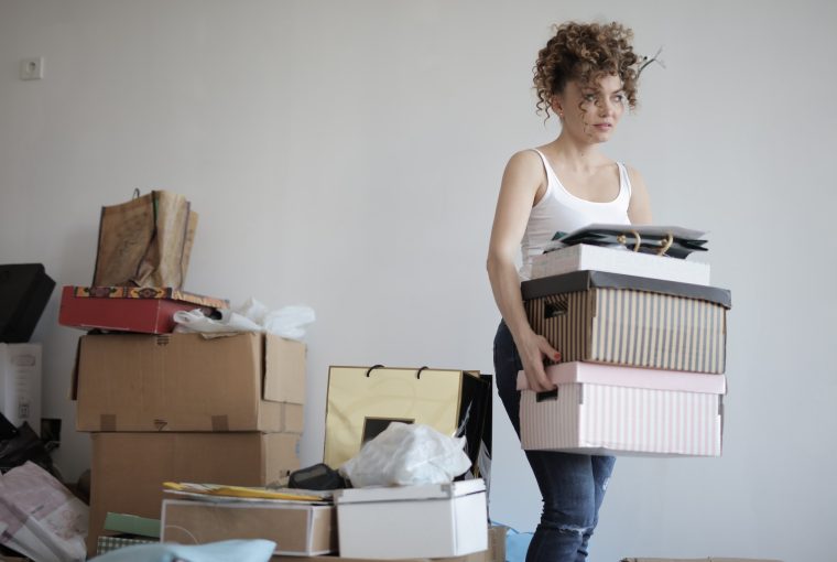 Women carying storage boxes in cluttered room