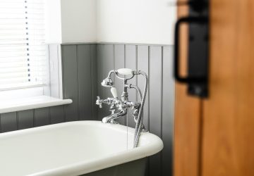 Roll top bath in bathroom with grey wall panelling